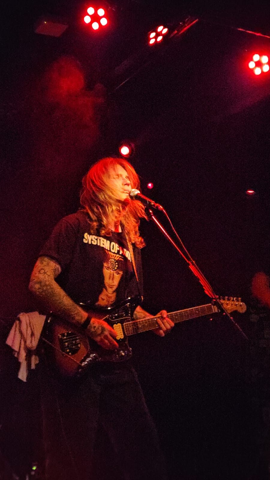 Gitarist en zang onder rood podiumlicht